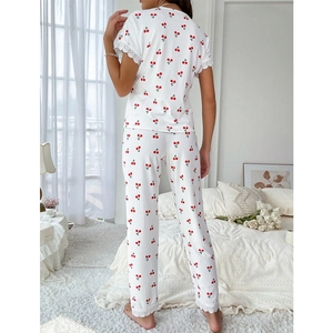 Women's white cherry print pajama set with lace trim and short sleeves in a bedroom setting