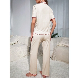 Detail of cream pajama set with contrasting red wavy edges on sleeves and hem