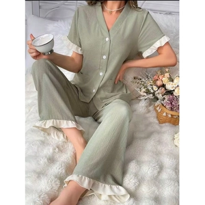 Détail de pyjama col en V vert sauge avec poignets à volants blancs et boutons