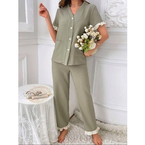 Détail d'un ensemble de pyjama vert sauge avec volants blancs et fermeture boutonnée
