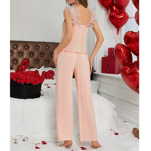 Pink satin V-neck sleepwear set with ruffled straps in a romantic bedroom setting