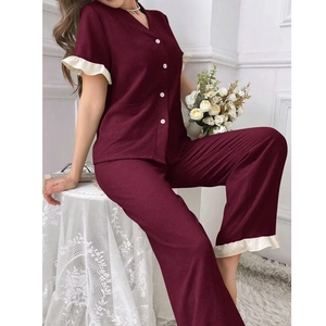 Détail d'un pyjama bordeaux avec col en V, volants crème aux poignets et boutons blancs