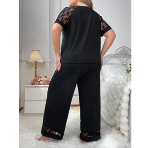 Women's black lace pajama set with short sleeve top and pants, back view in a bedroom