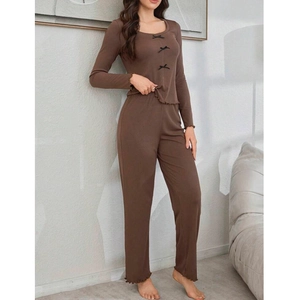 Ensemble pyjama marron pour femme avec nœuds et bords volantés dans un décor intérieur