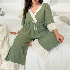 Women's V-neck green pajama set with white lace trim and bow on a white bed