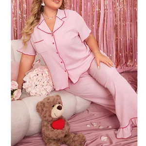 Detail of pink plus-size pajama set featuring contrast piping on lapels and ruffled cuffs
