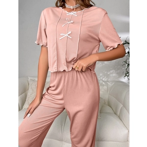 Detail of pink pajama set with ruffled edges, small white bows, and ribbed fabric texture