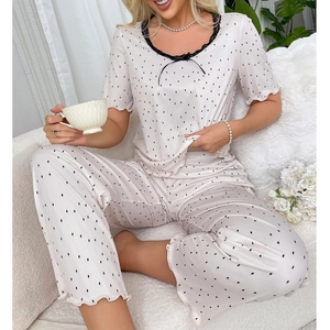 Close-up of pink polka dot silk pajama set with black lace trim and bow detailing