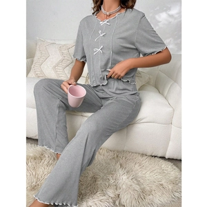 Close-up of gray pajamas with white bow details and ruffled hems in a cozy home setting