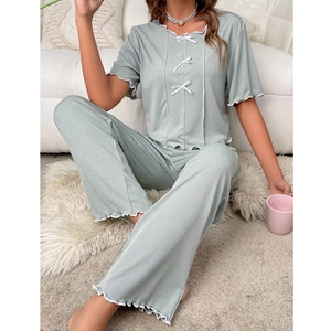 Close-up of light green pajama set with white bow ties and lettuce-edge detailing