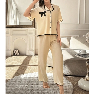 Women's cream loungewear set with short sleeve top and long pants featuring black piping