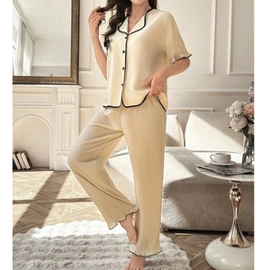Detail view of cream pajamas with black contrast piping and elegant ruffle trim