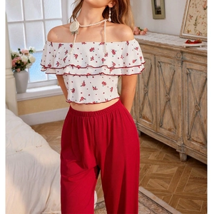 Détail du haut à fleurs à épaules dénudées avec volants et pantalon large rouge