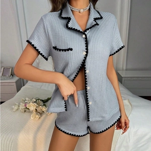 Detail of light blue waffle texture pajama set with black scalloped trim and white buttons