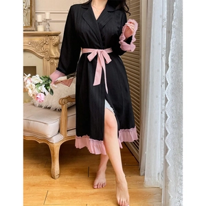 Détail d'un peignoir noir plissé élégant avec volants roses et ceinture assortie