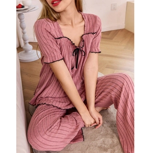 Detail view of pink ribbed knit pajama set with delicate black ruffle trim and bow accents