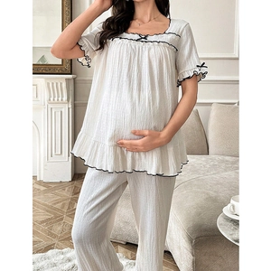Detail of white maternity loungewear featuring black wavy lace trim and bow accents