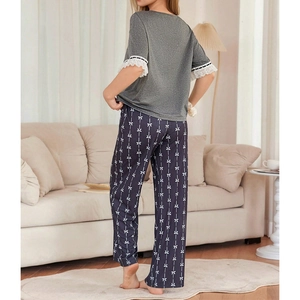 Women's pajama set with lace-trimmed short sleeve top and bow-print trousers in a cozy room