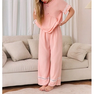 Détail du pyjama rose avec bordure en dentelle blanche et petit nœud délicat au décolleté