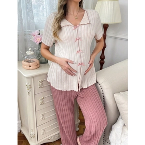 Detail of maternity loungewear featuring a ribbed V-neck top with pink bows and trousers