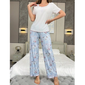 Detail of female pajamas set showing white top with pink bow and floral cat print pants