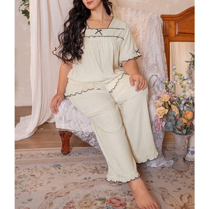 Detail of vintage cream pajama set with black wave lace trim and delicate ribbon bows