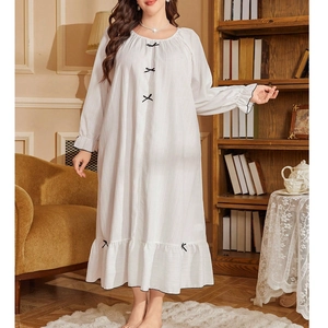 Close-up of white long-sleeve nightdress featuring black bow accents and ruffled edges