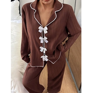 Détail d'un ensemble de pyjama plissé marron avec passepoil blanc et boutons nœuds