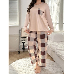 Women's pajama set featuring pink long-sleeve top and plaid trousers in cozy home setting