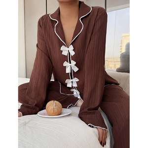 Détail d'un pyjama plissé marron foncé avec nœuds blancs et liserés contrastés élégants