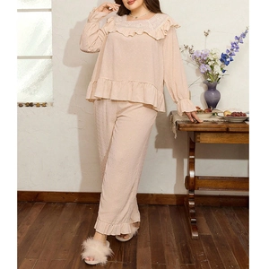 Detailed view of lace neckline and ruffled cuffs on textured beige lounge sleepwear