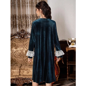 Elegant emerald green velvet lounge dress with white lace cuffs in a vintage interior