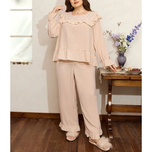 Detailed close-up of Swiss dot texture and ruffle hem on soft pink long-sleeve pajamas set
