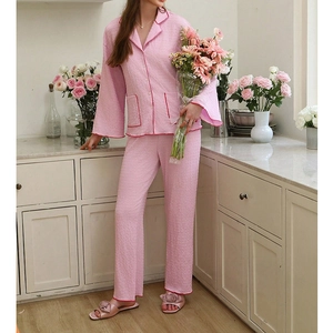 Detail of pink long-sleeved pajamas with red piping and textured seersucker fabric finish