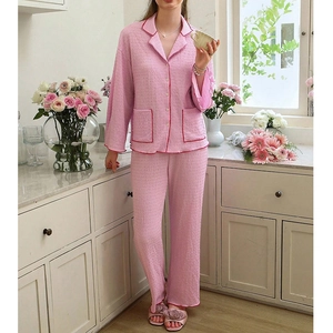 Women's pink seersucker pajama set with long sleeves, lapel collar, and red piping details