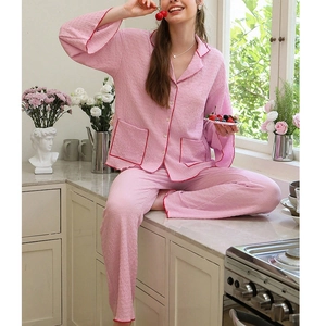 Pink women's long-sleeve pajama set with red contrast piping and classic lapel collar
