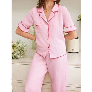 Detail of pink pajama set with red contrast piping and textured seersucker fabric finish