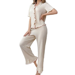 Women's two-piece cream pajama set with pink ruffle trim and seersucker texture