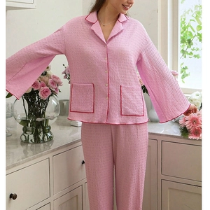 Detail of pink pajama set featuring pleated texture and contrasting red piping on pockets