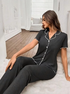Detail of grey short-sleeve pajama top with contrast white piping and button closure