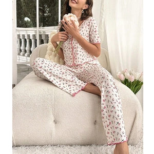 Floral pajama set with short sleeves and long pants featuring pink ruffled trim on cream fabric