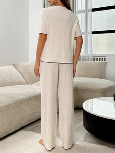 Détail d'un pyjama crème pour femme avec bordure noire et tissu à texture ondulée au dos