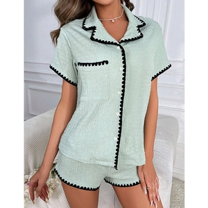 Détail d'un ensemble pyjama vert menthe avec bordure noire festonnée et tissu texturé
