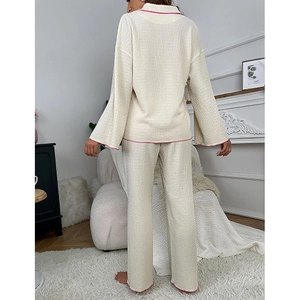 Detail view of cream lounge set featuring contrast pink piping on back hem and sleeve cuffs