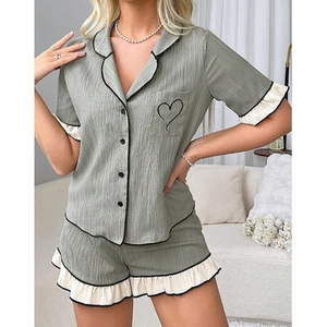 Detail view of heart embroidery on ruffled sleeve of these green women's pajamas