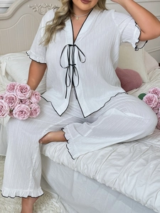 Detail of white pajamas with black contrast piping and elegant ribbon bow tie