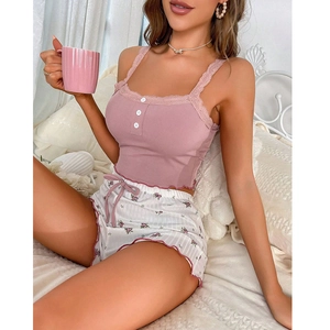 Schlafanzug-Set für Damen mit rosa Trägertop und geblümten Shorts in gemütlicher Umgebung