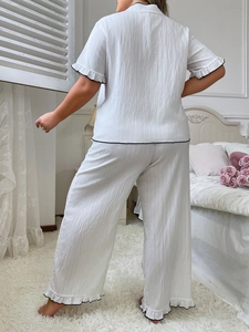Close-up back view of white pajama set with black piping and ruffle hem details