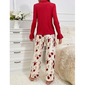 Women's pajama set featuring a red long-sleeve top and floral print pants in a home setting