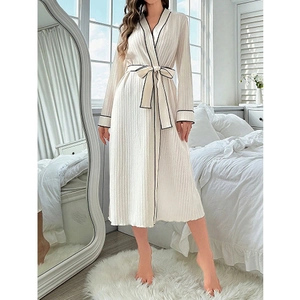 Detail of white knit robe featuring black contrast piping and adjustable waist tie